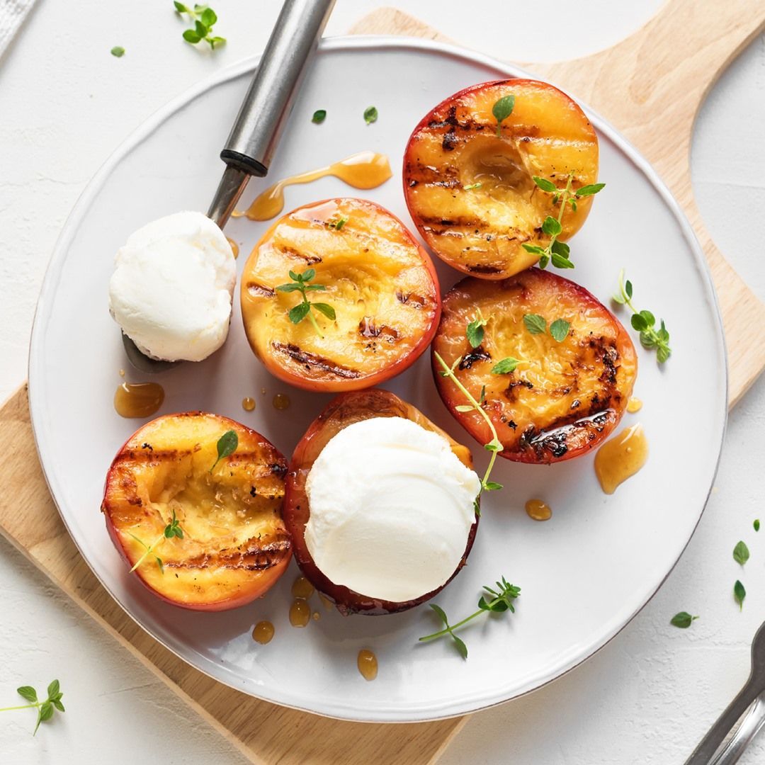 Grilled Peach Halves with Ice Cream and Thyme Sprigs on A White Plate — Cedar Park Supermarket In Taranganba, QLD