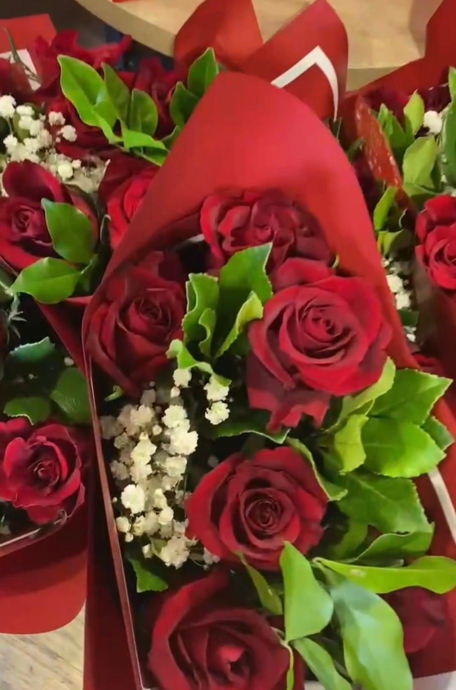 Bouquets of red roses wrapped in red paper with white baby's breath and green leaves — Cedar Park Supermarket In Taranganba, QLD