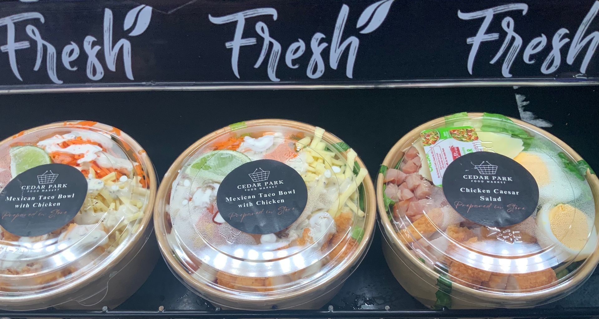 Three Clear-Lidded Fresh Food Bowls on A Display Shelf — Cedar Park Supermarket In Taranganba, QLD