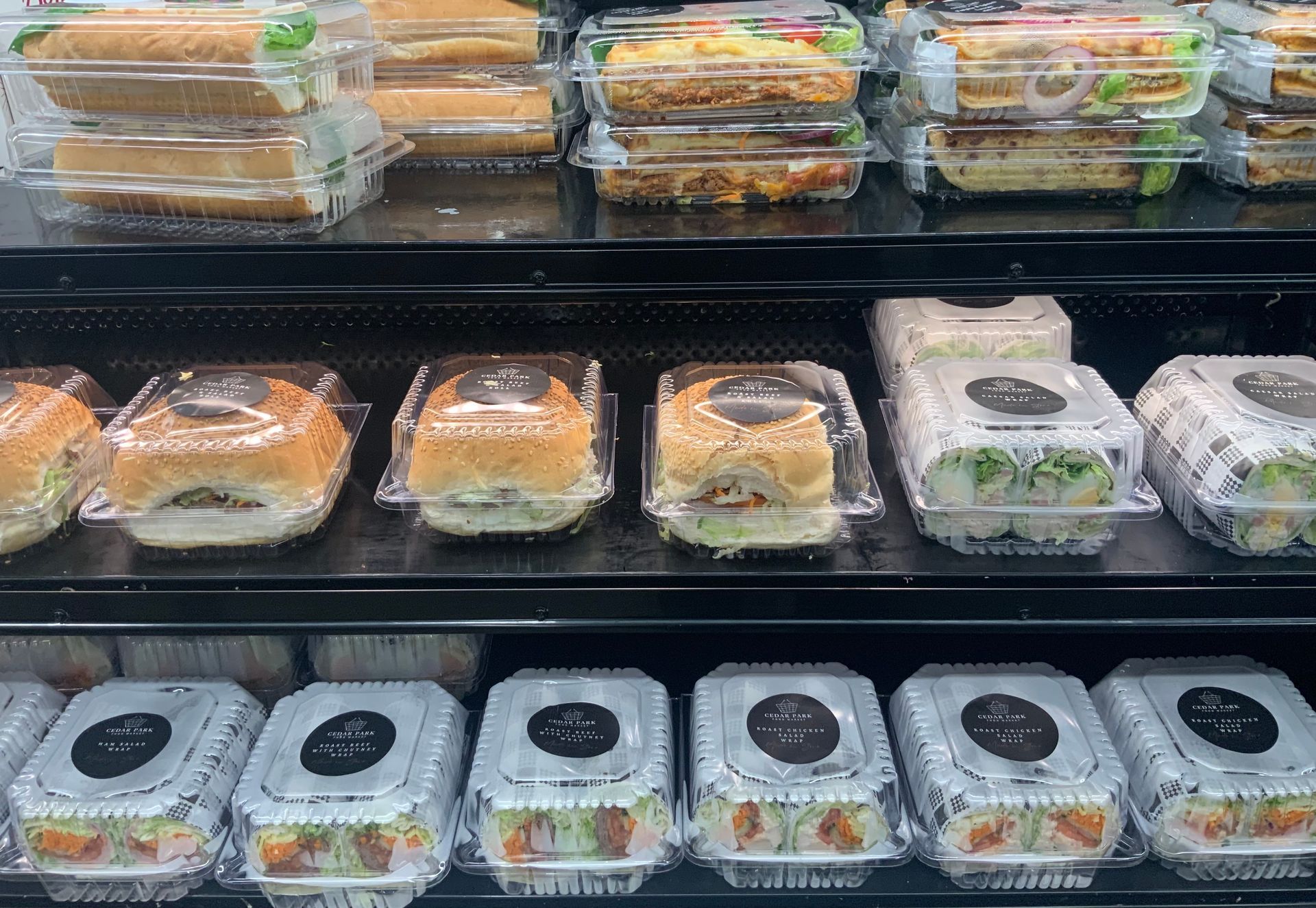 Assorted packaged sandwiches and wraps displayed in a refrigerated deli case — Cedar Park Supermarket In Taranganba, QLD