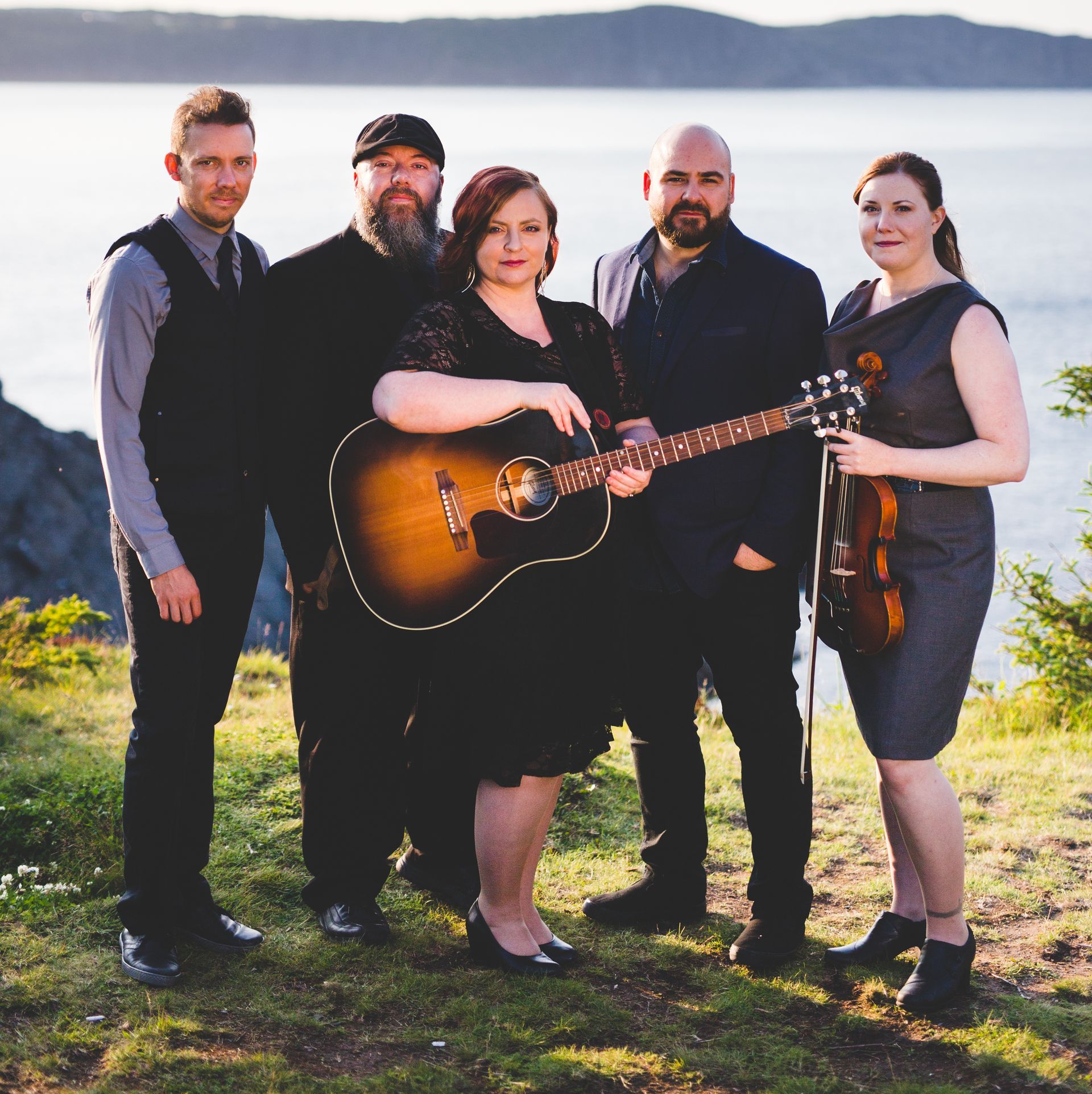 A group of people posing for a picture with one woman holding a guitar