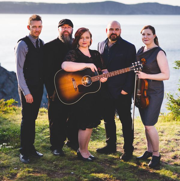 A group of people posing for a picture with one woman holding a guitar
