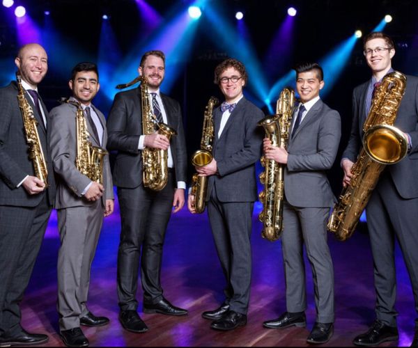 A group of men in suits holding saxophones on a stage