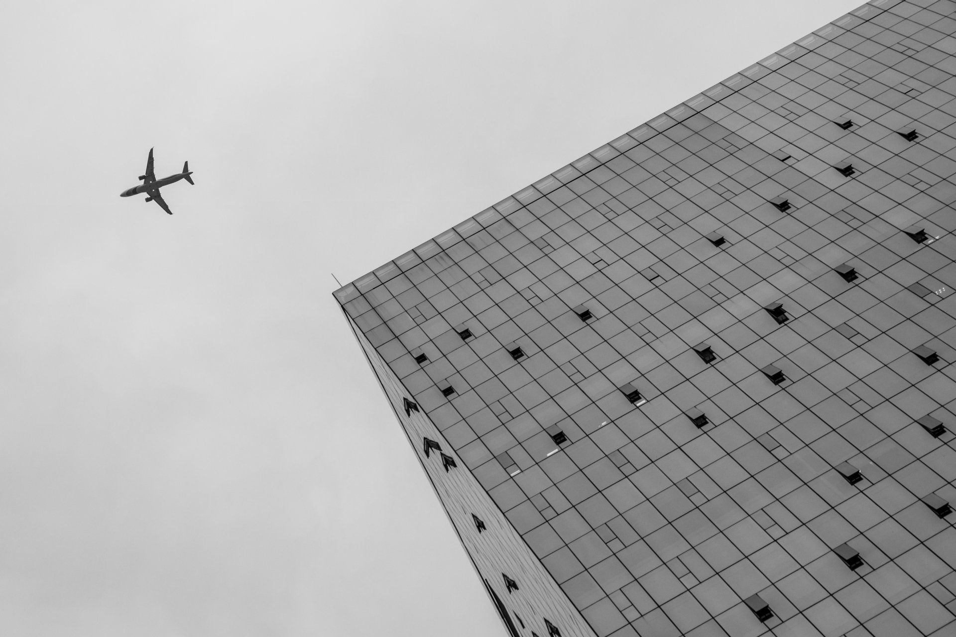 low angle view building plane flying near it sky