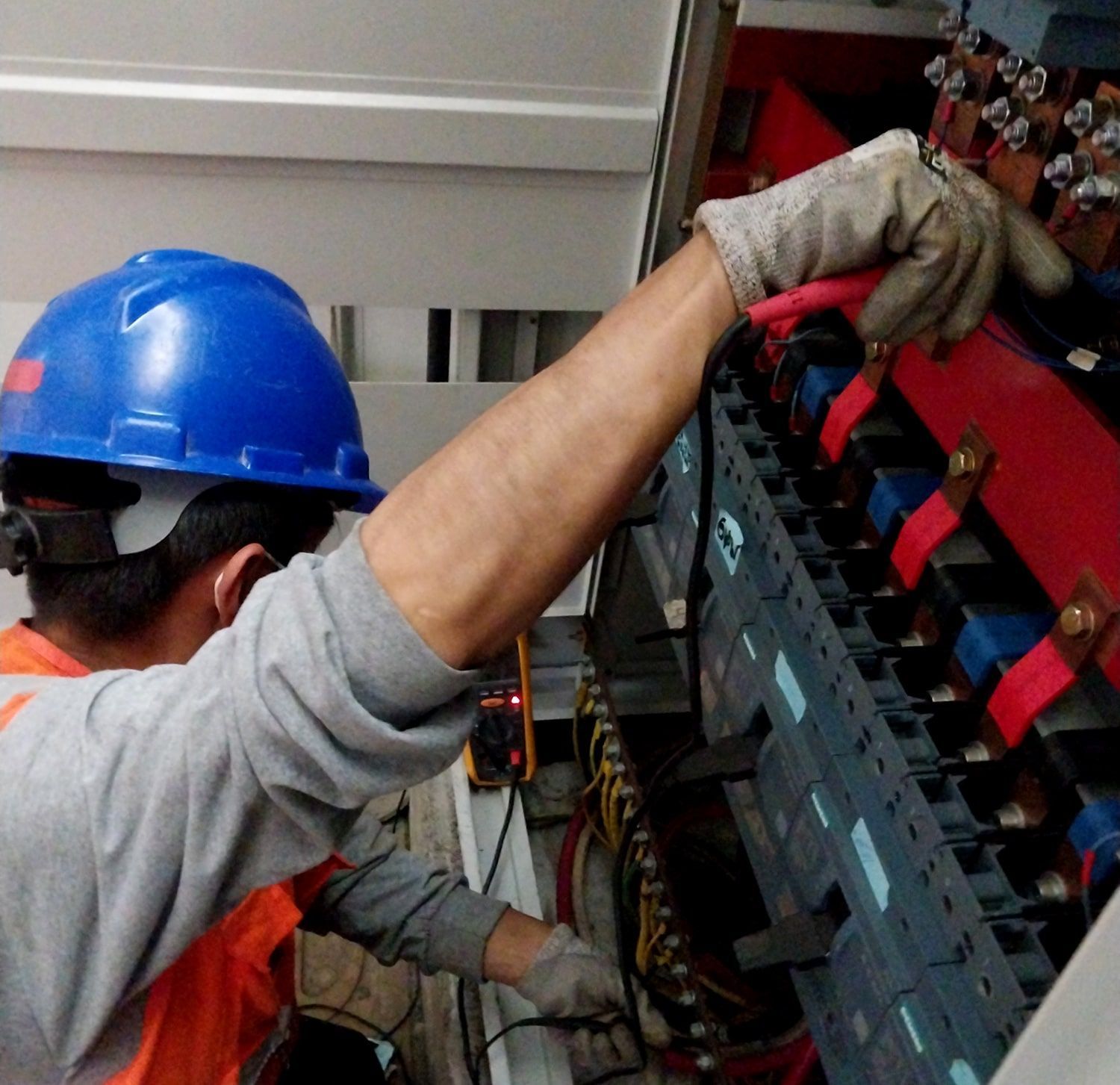 Un hombre que lleva un casco azul está trabajando en una caja eléctrica.