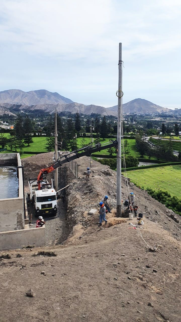 Un camión blanco con una grúa acoplada circula por un camino de tierra.