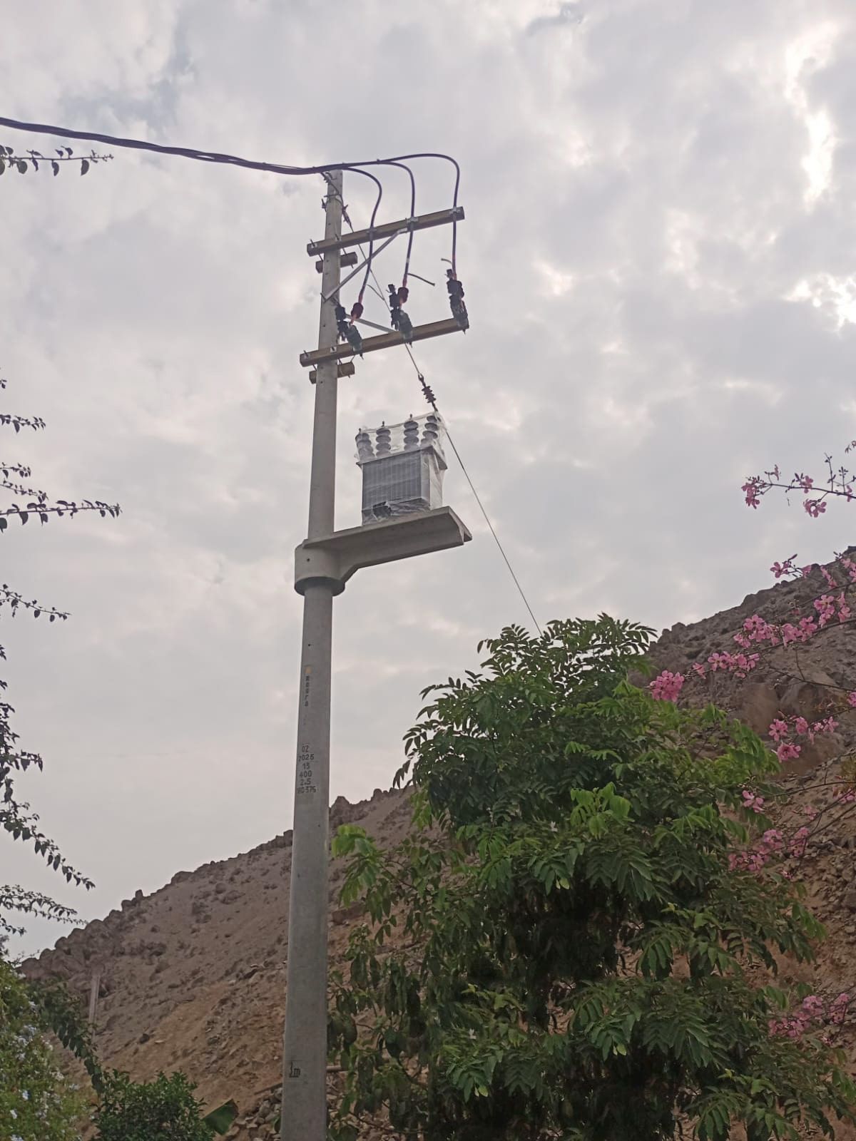 Un poste eléctrico con un transformador encima.