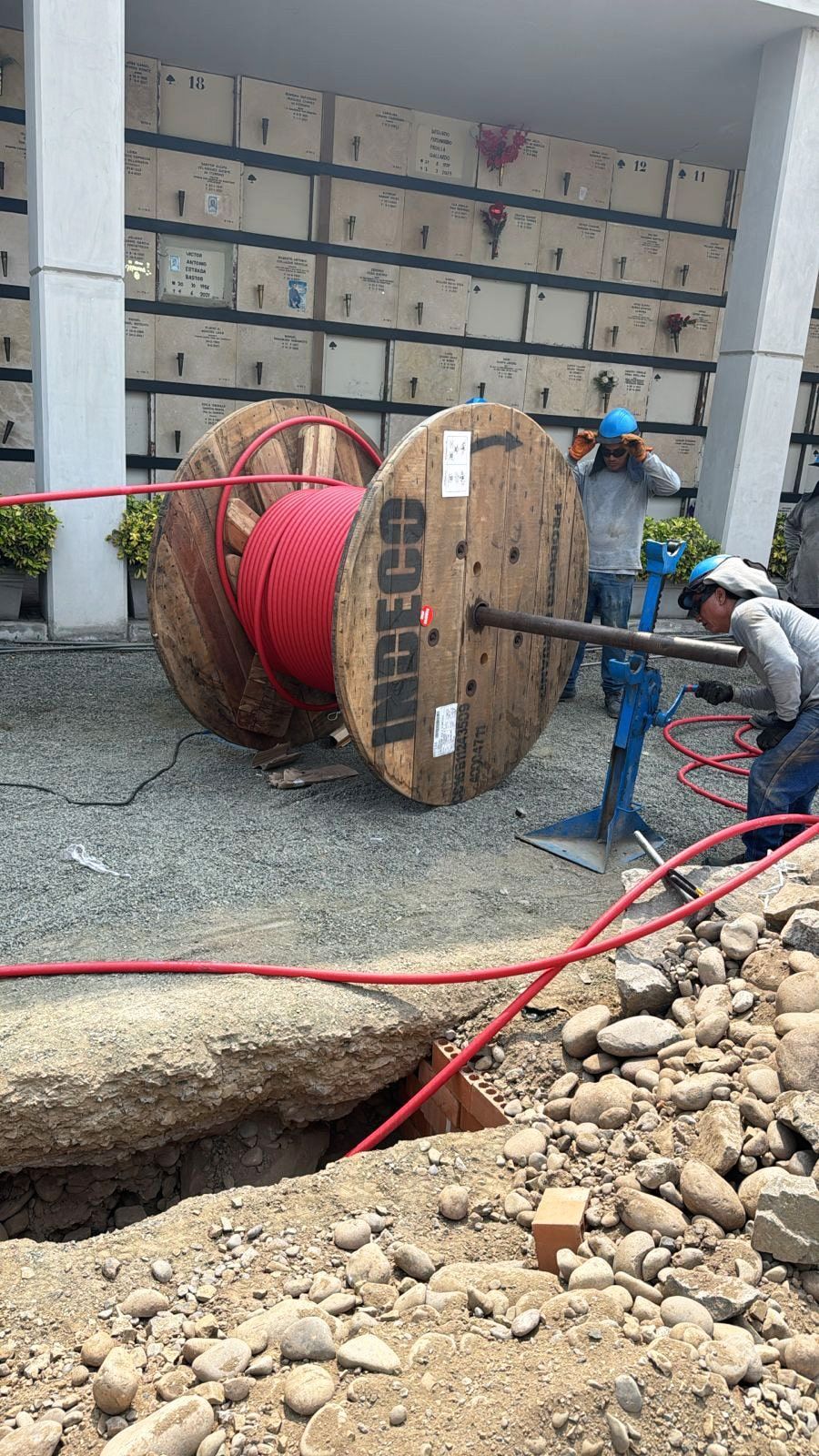 Se está cargando un gran carrete de cable de madera en un agujero en el suelo.