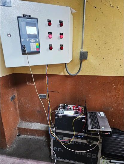 Una computadora portátil está junto a un panel de control en una habitación.