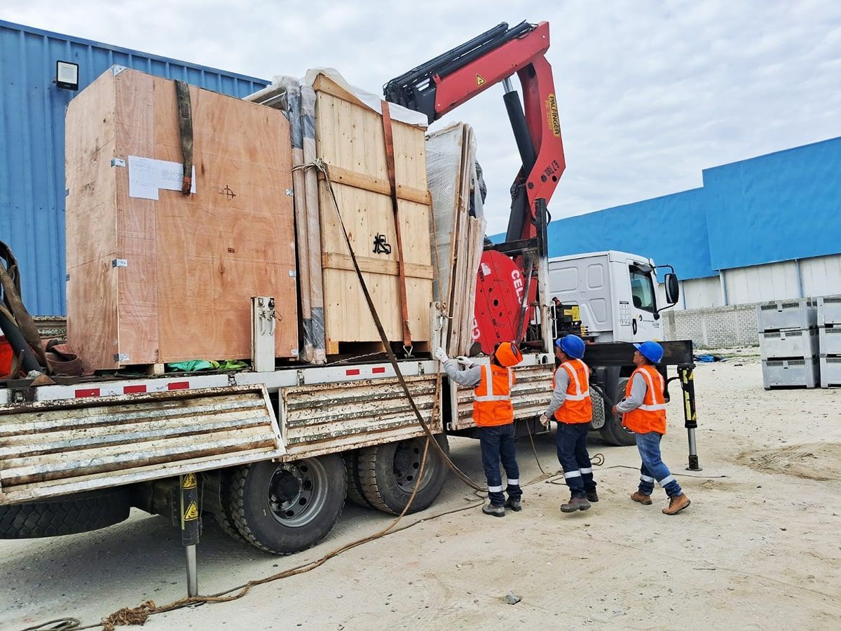 Un camión está siendo cargado con cajas de madera mediante una grúa.