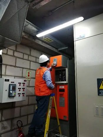 Un hombre está de pie en una escalera trabajando en una caja de naranjas.