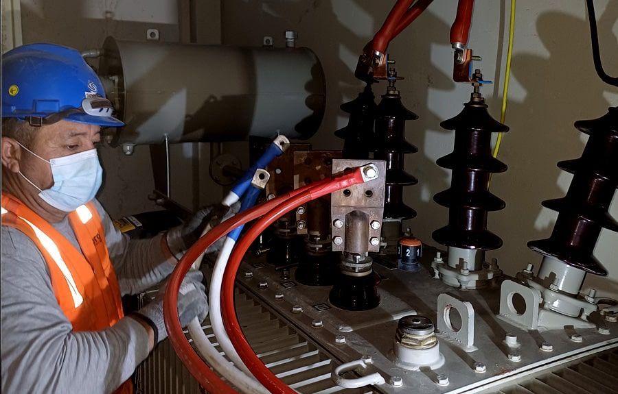 Un hombre con una máscara está trabajando en un transformador.