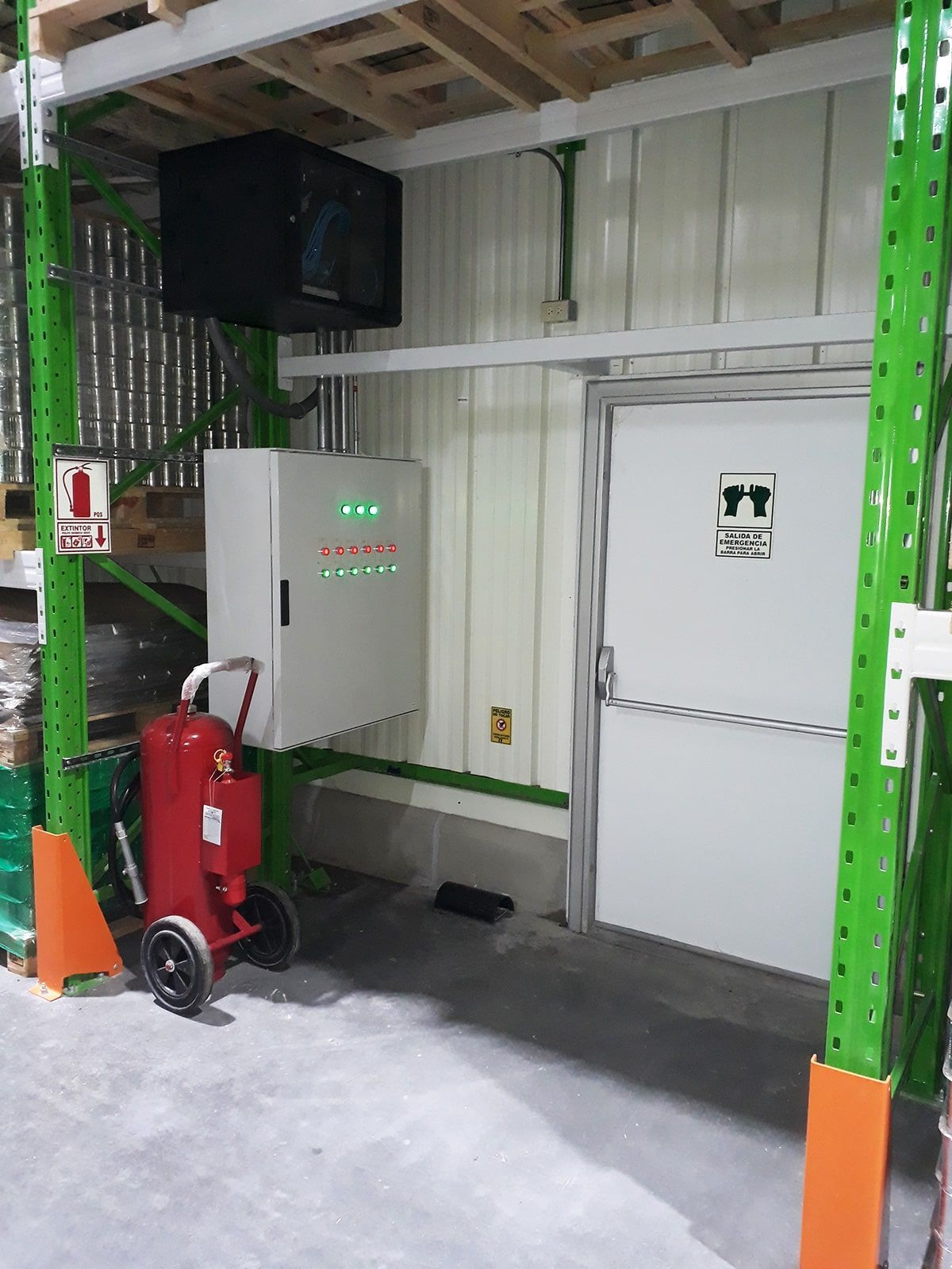 Un almacén con estantes verdes y un extintor rojo.