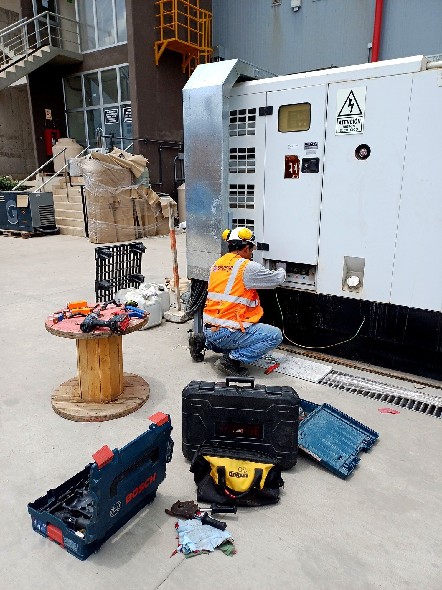 Un hombre está trabajando en un generador afuera de un edificio.