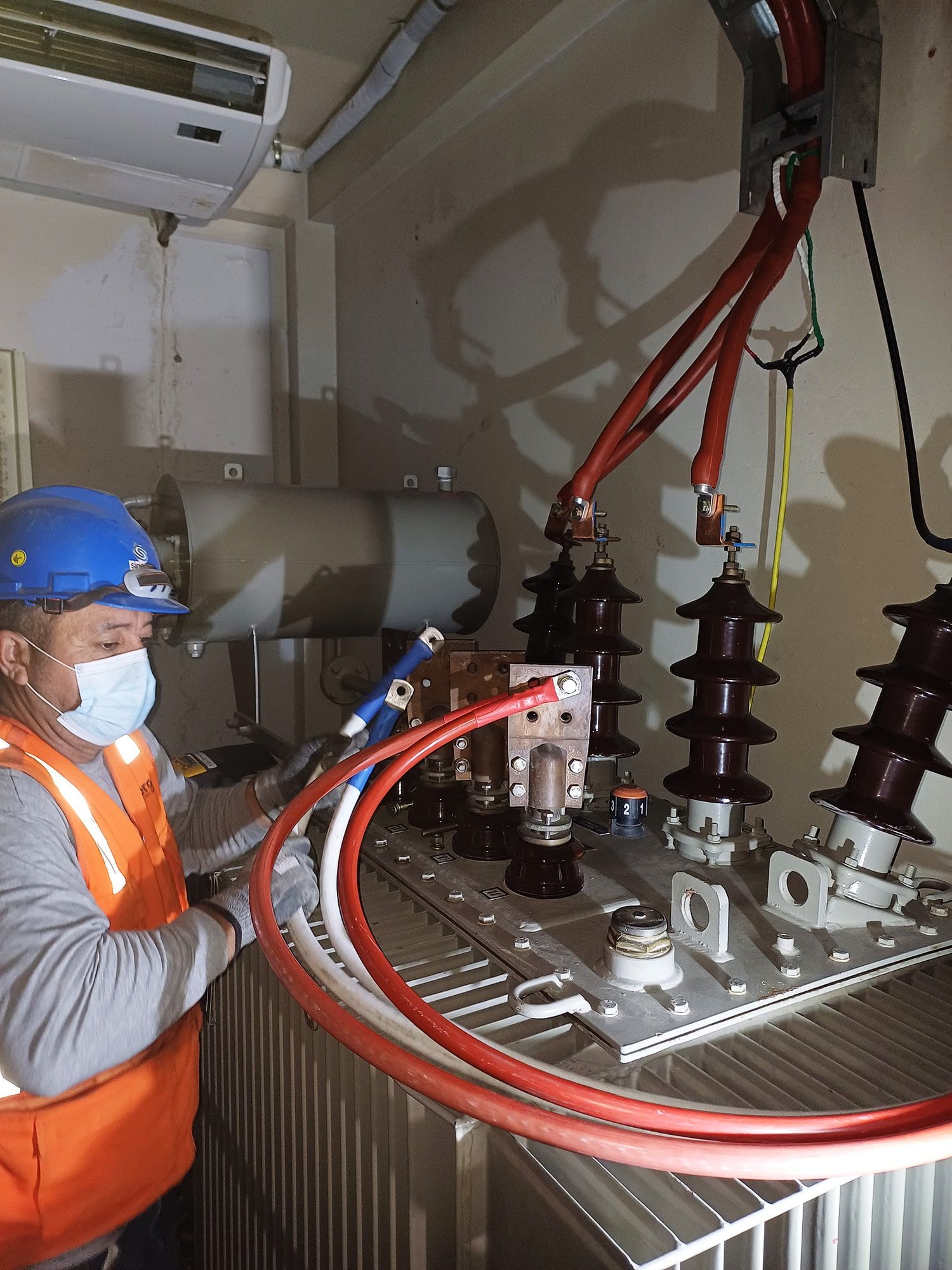Un hombre que lleva una máscara está trabajando en un transformador.
