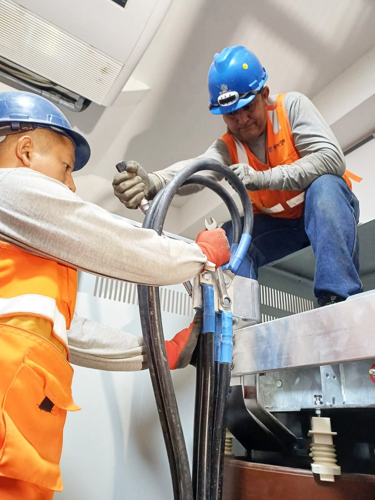 Dos hombres con cascos de seguridad están trabajando en una máquina.