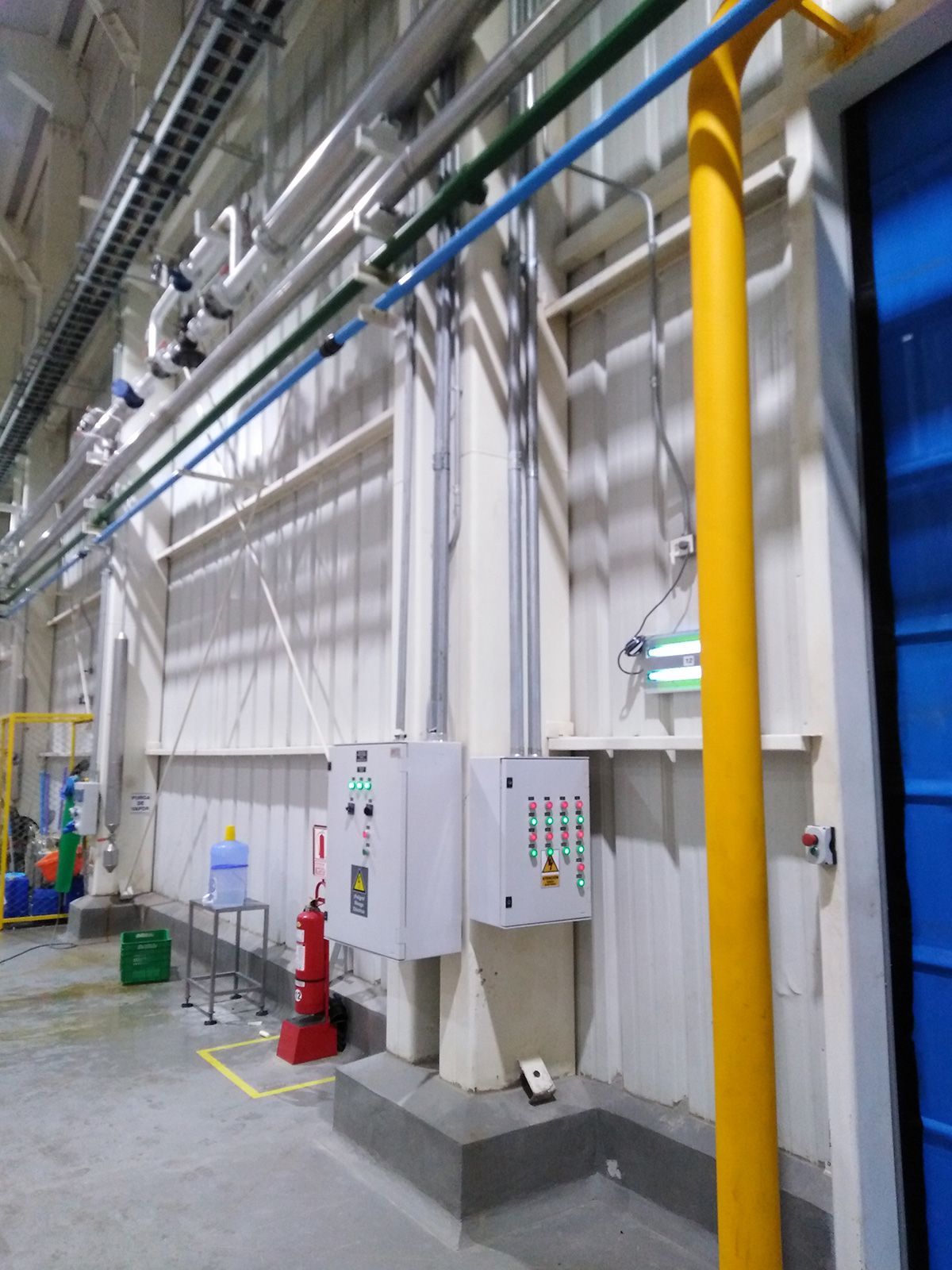 Una habitación con muchas tuberías y una puerta azul.