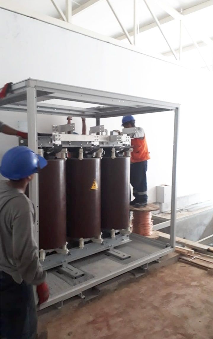 Un hombre que lleva un casco azul está trabajando en un transformador.