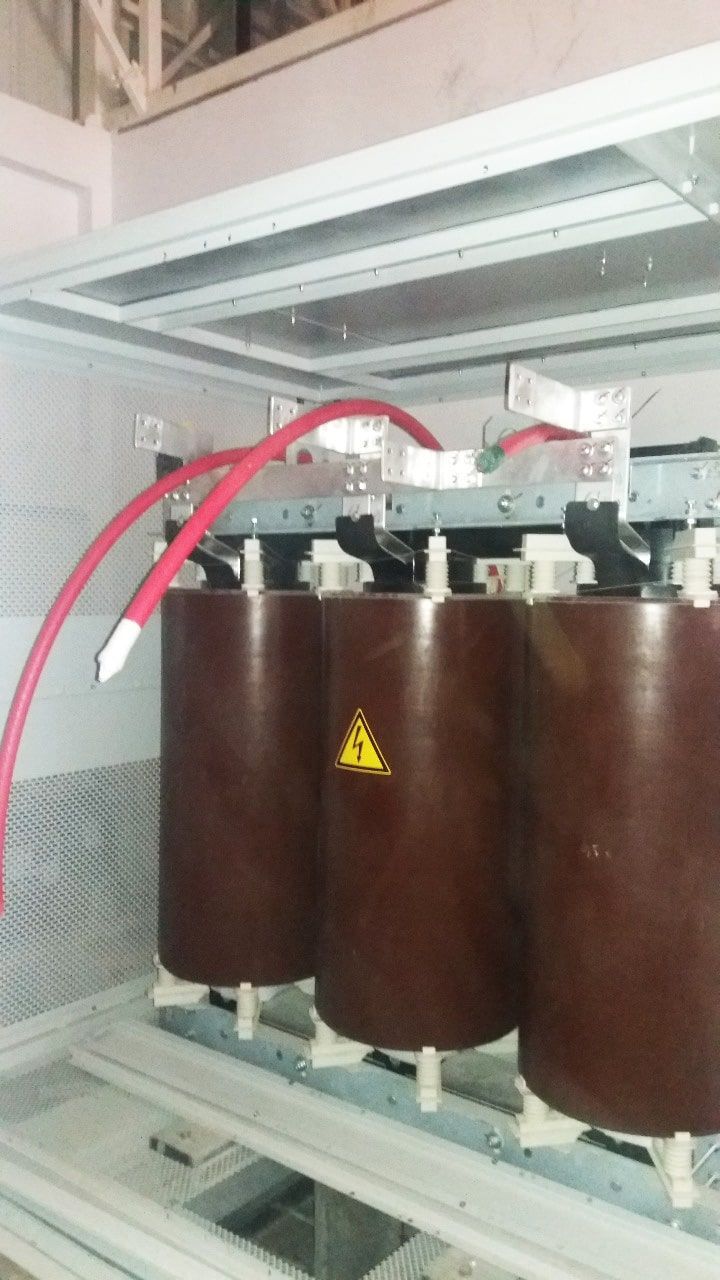 Un primer plano de tres transformadores eléctricos marrones con cables rojos que salen de ellos.