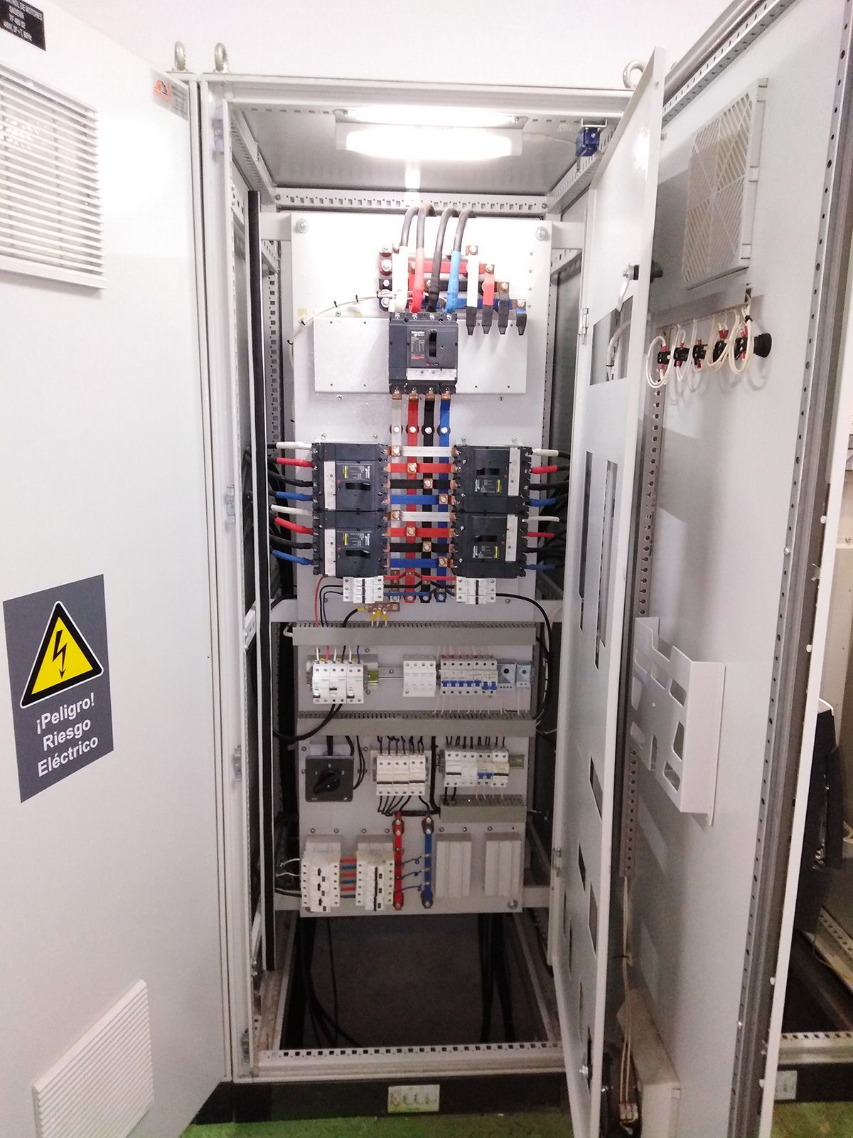 Un gran armario eléctrico con las puertas abiertas y un cartel en la pared.