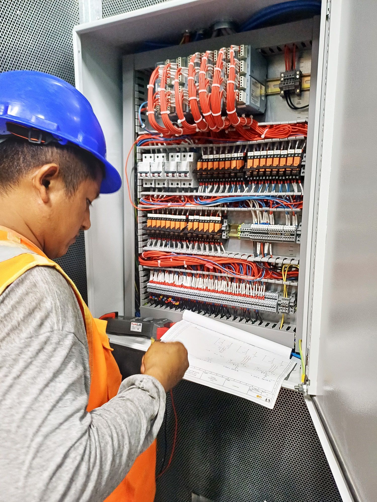 Un hombre que lleva un casco está trabajando en una caja eléctrica.