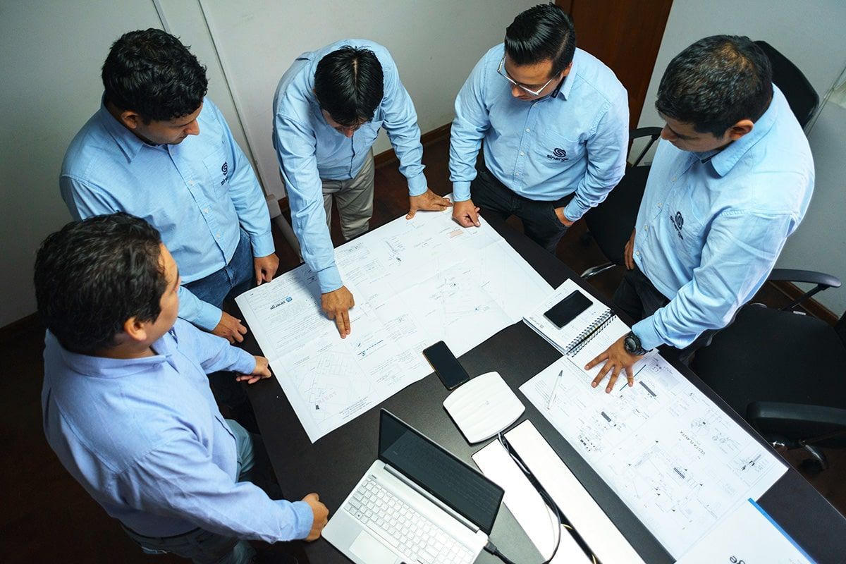 Un grupo de hombres está sentado alrededor de una mesa mirando un plano.