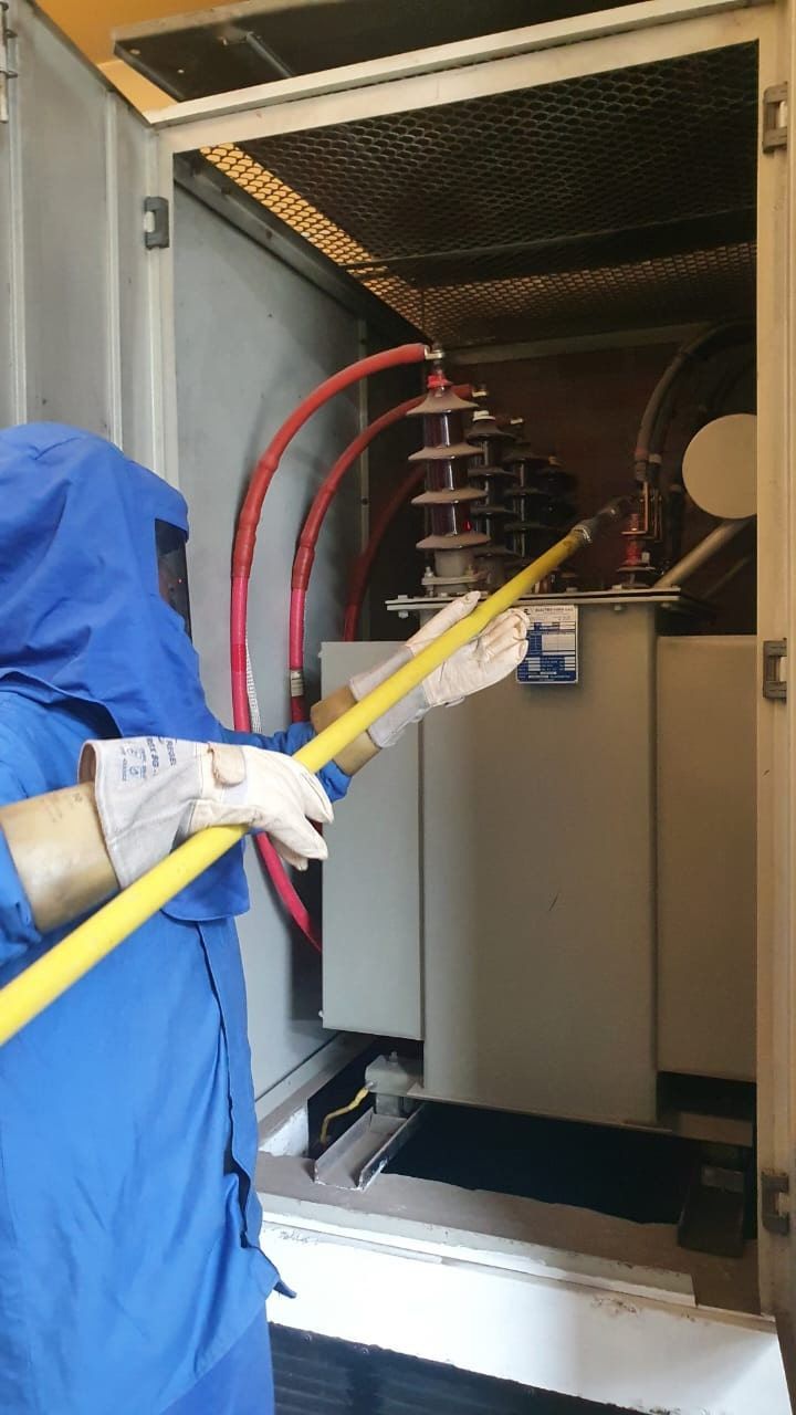 Un hombre con un traje azul está limpiando una caja eléctrica con un trapeador.