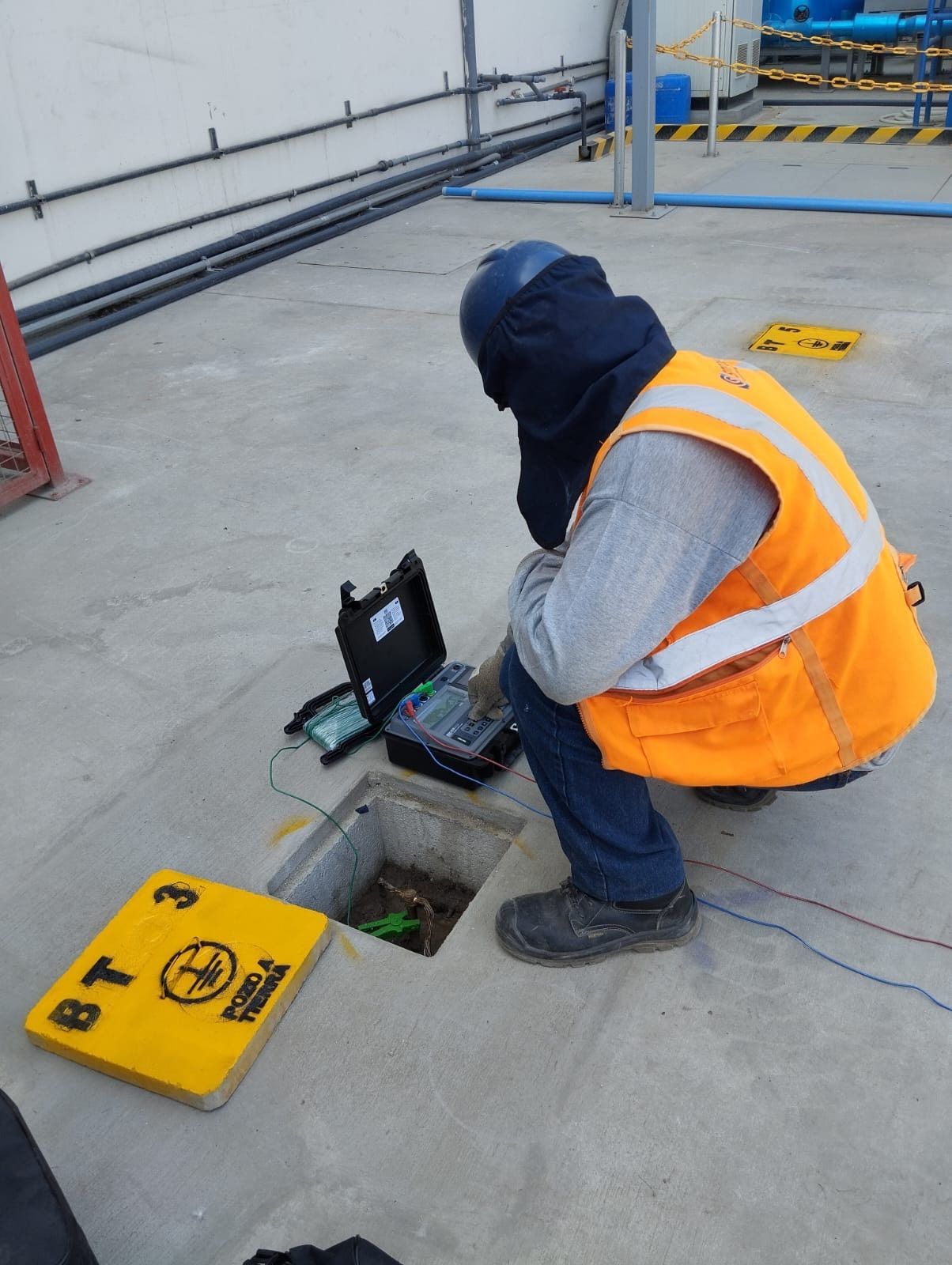 Un hombre con un chaleco naranja está trabajando en un dispositivo en una alcantarilla.