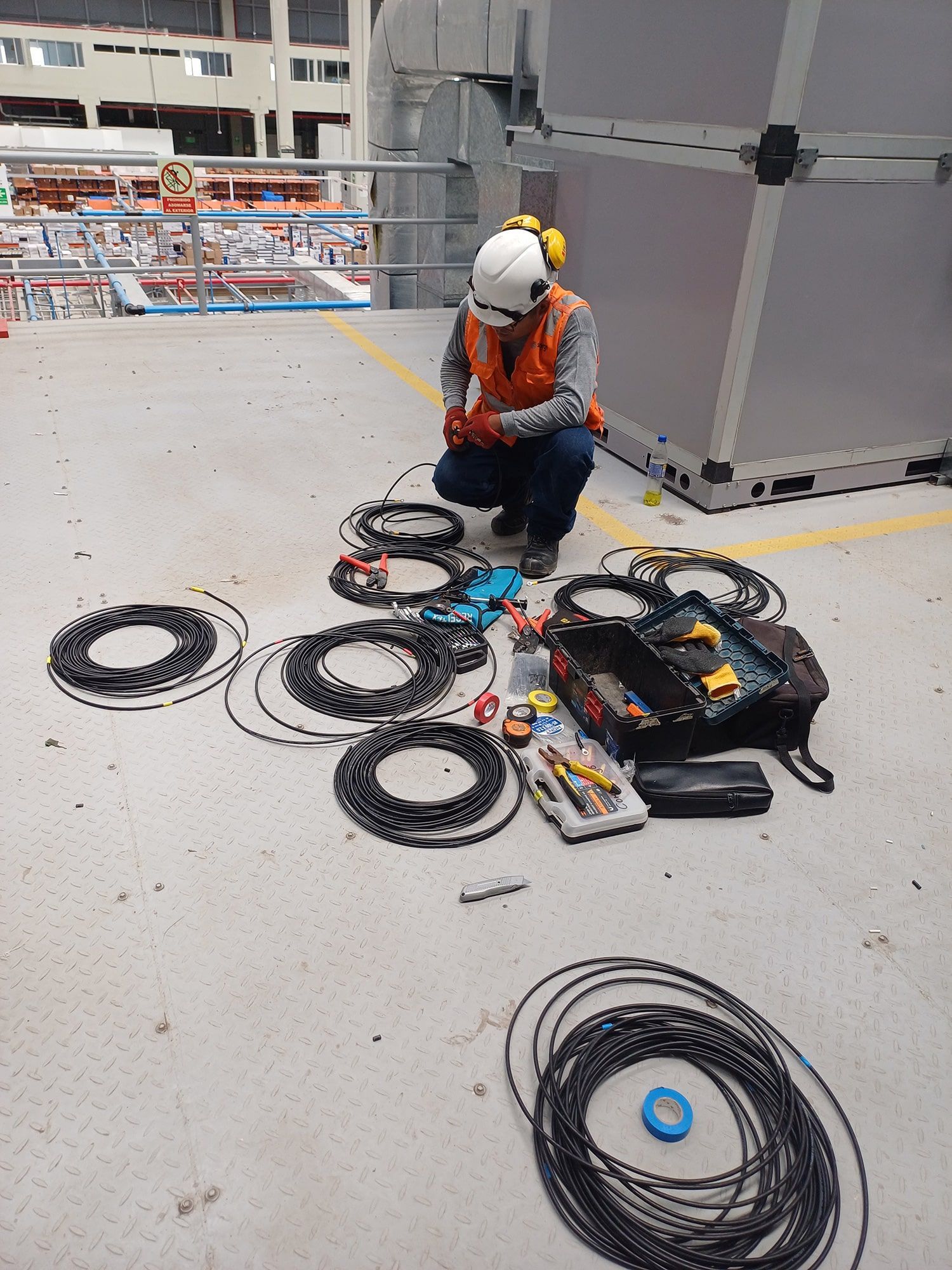 Un hombre está trabajando con un montón de cables en el suelo.