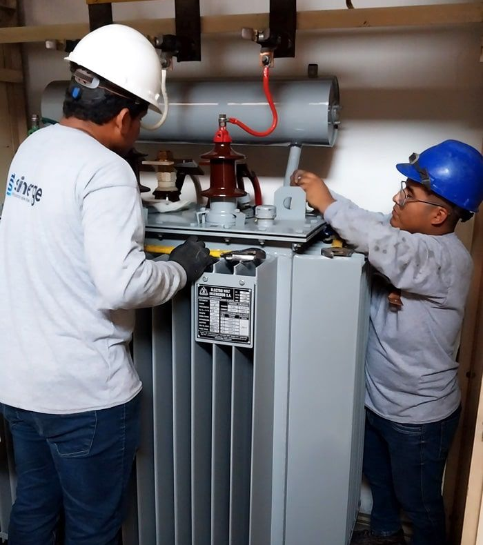 Dos hombres están trabajando en un transformador en una habitación.