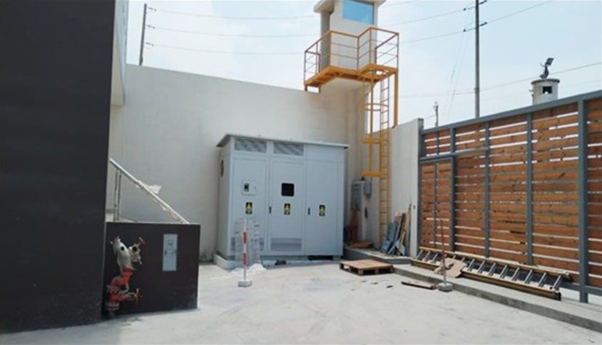 Un área vallada con una escalera y una torre al fondo.