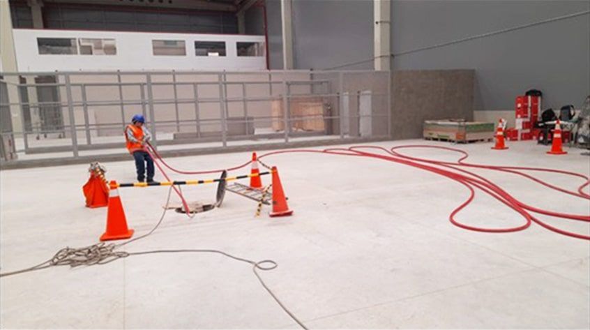 Un hombre está de pie en un almacén sosteniendo una manguera.