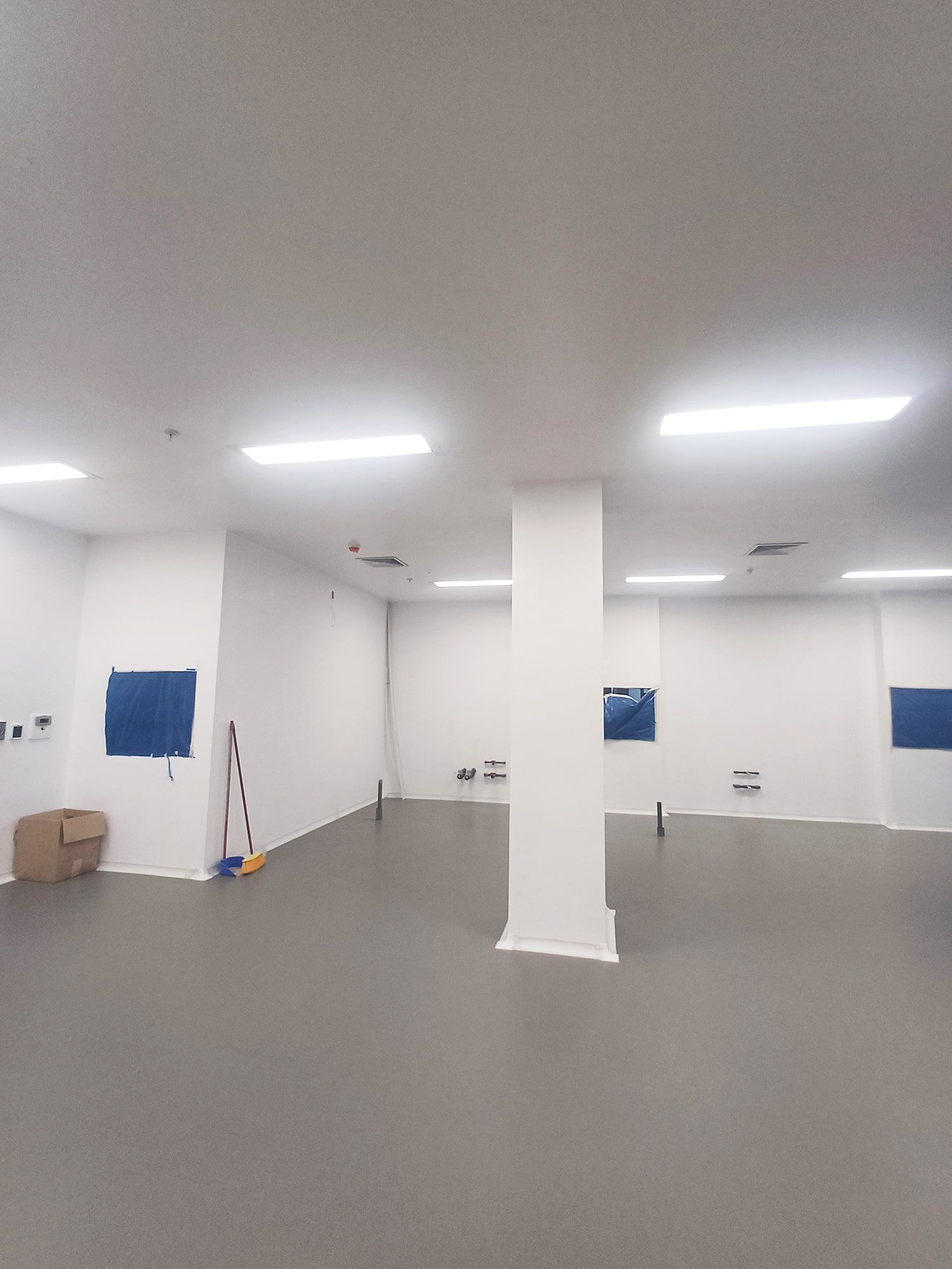 Una habitación grande con suelo gris y paredes blancas.