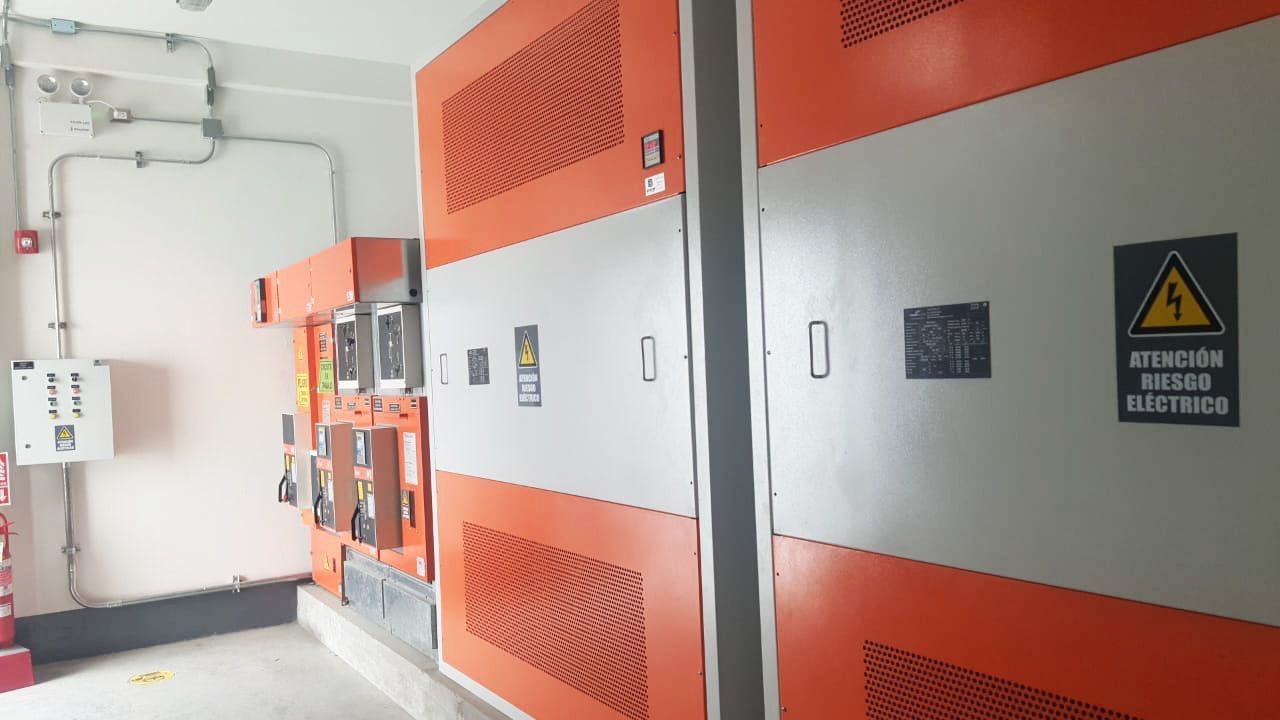 Una habitación con mucho equipo eléctrico y un cartel de advertencia en la pared.