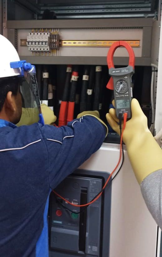 Un hombre con casco está usando una pinza amperimétrica