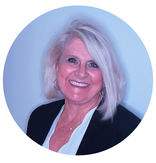 Woman with blonde hair smiles, wearing a black jacket and white blouse, inside a light blue circle.