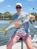 Man holding a large silver fish on a boat; sunny day.