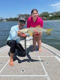 A man and a girl holding a large fish on a boat. The sunny day.