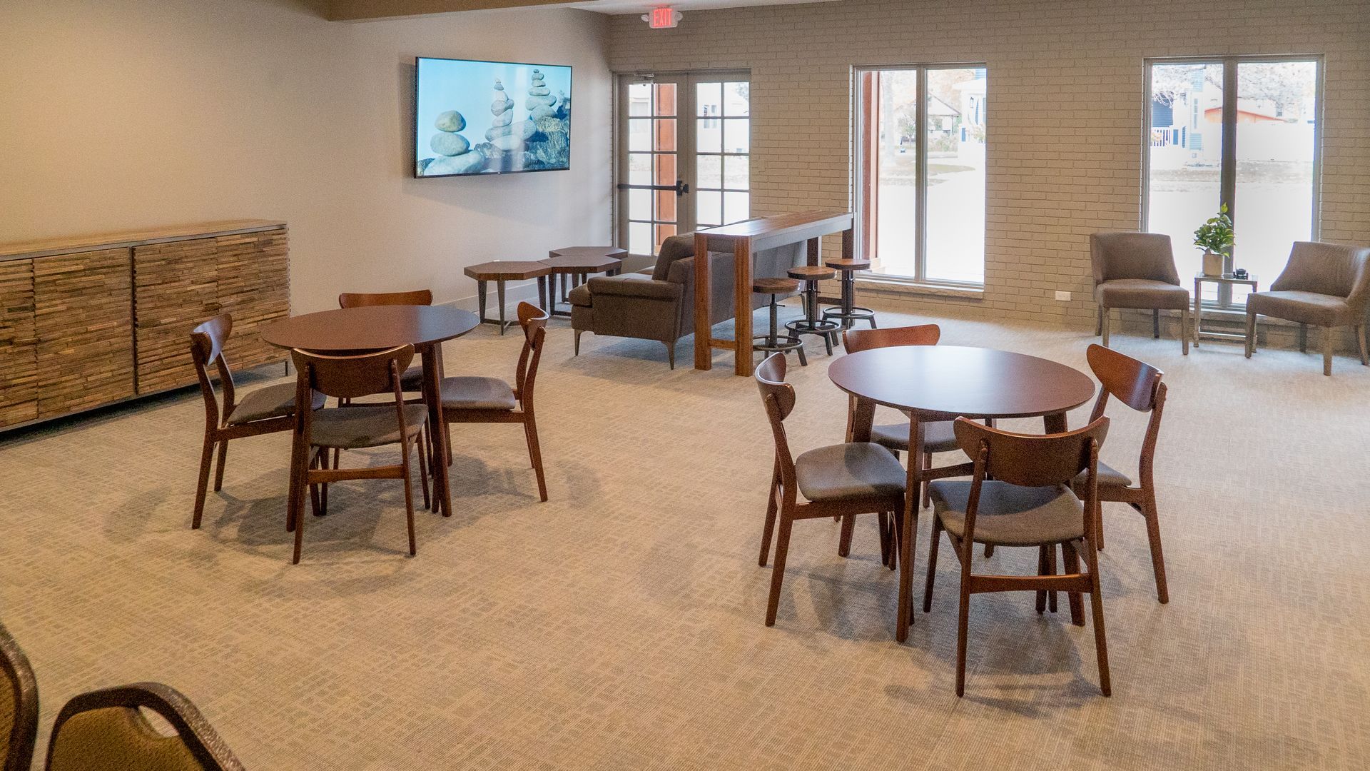 A large room with tables and chairs and a television on the wall.