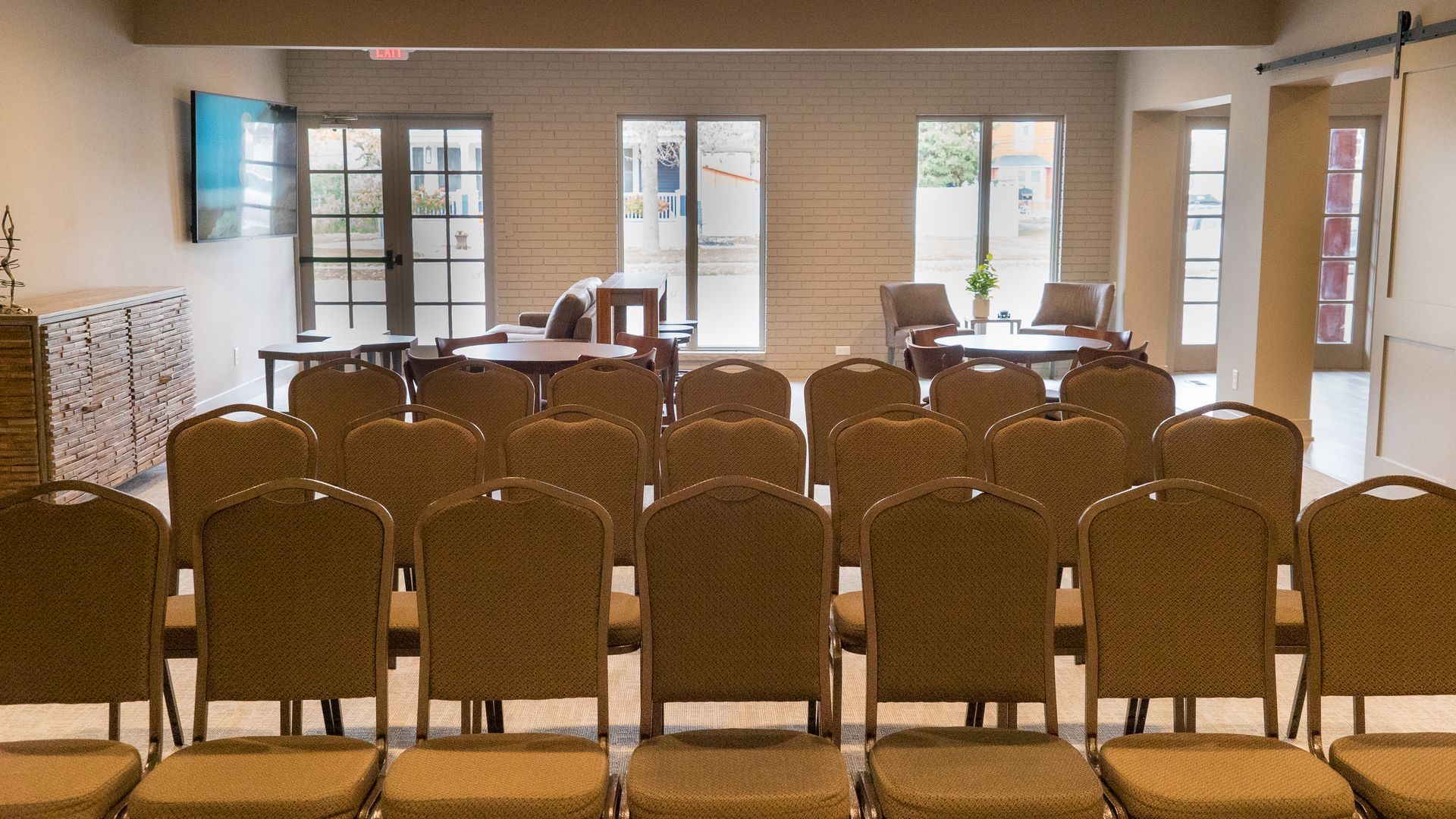 Rows of chairs are lined up in a room with tables and windows.