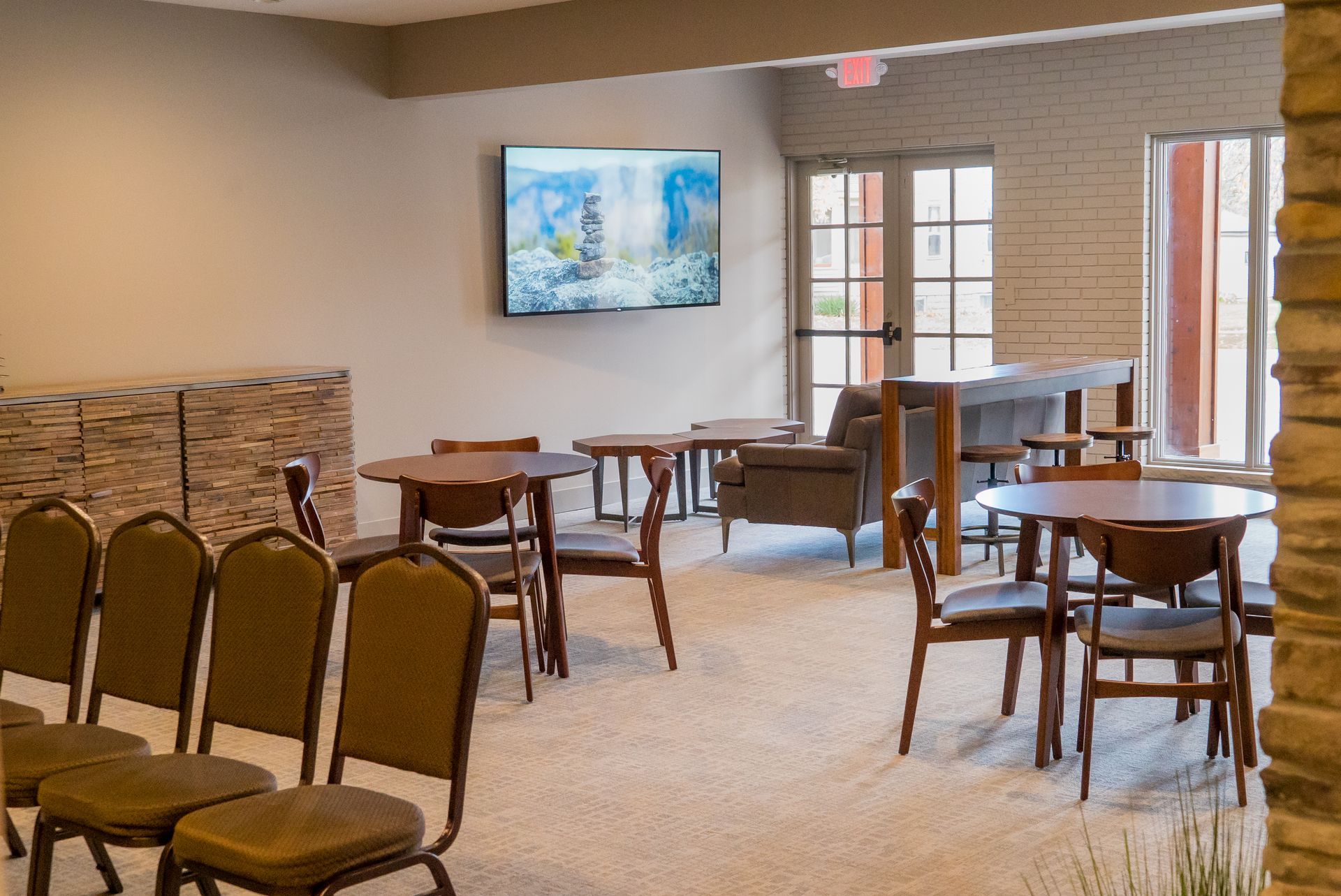 A room with tables and chairs and a television on the wall.