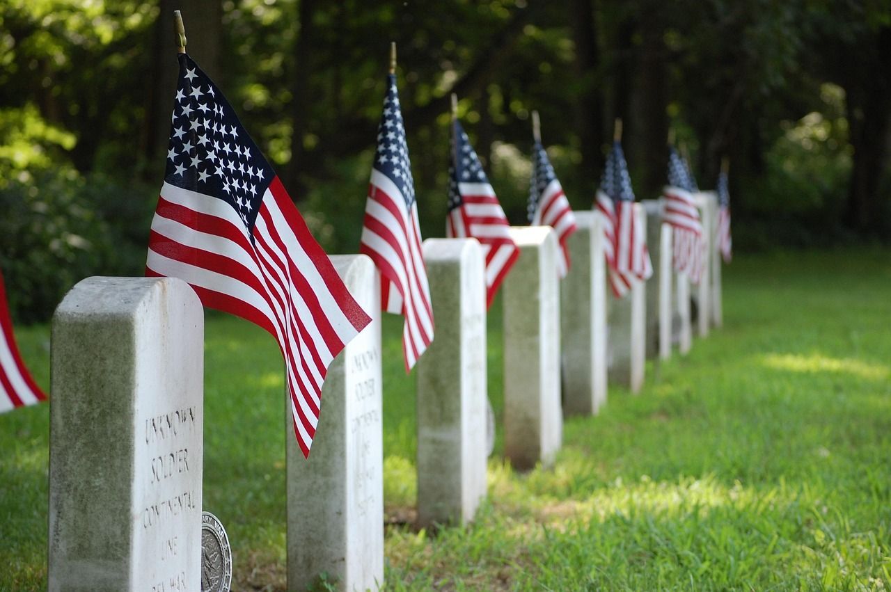 Rows of graves in a United States military cemetery with American flags on each headstone