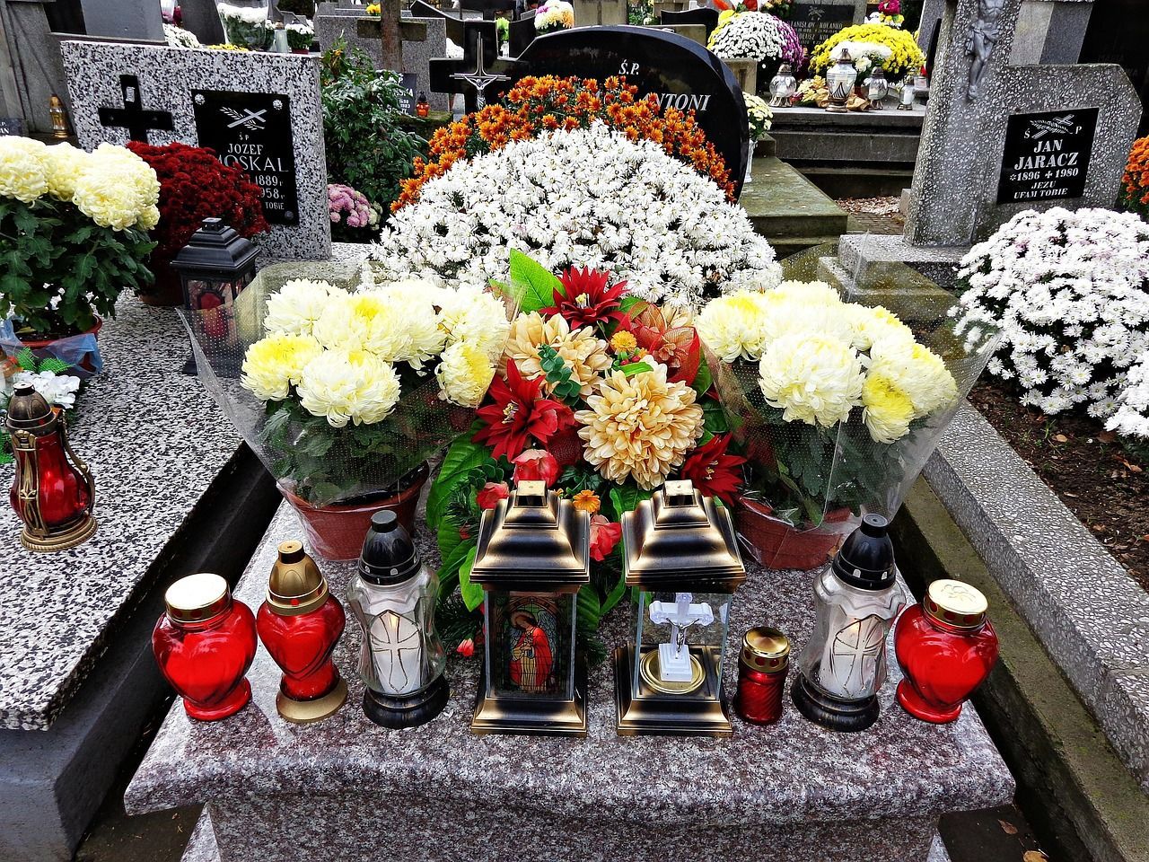 Grave decorated with flowers, lanterns, and candles surrounded by chrysanthemums in a cemetery