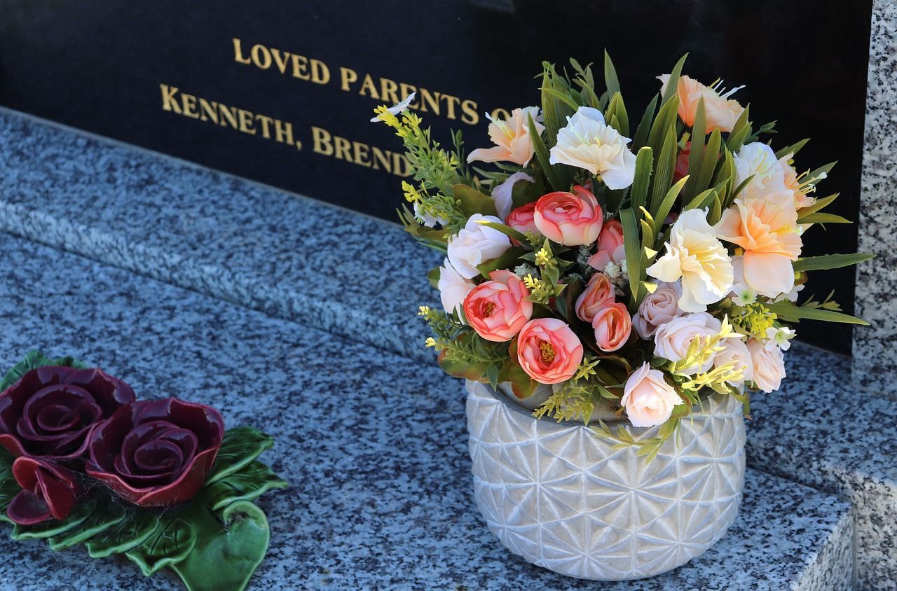 Bouquet of artificial flowers placed on a granite headstone at a cemetery memorial