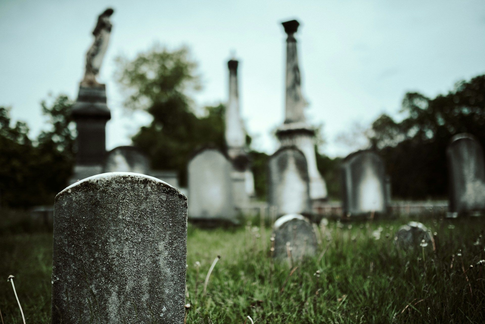 Gray concrete cross standing on a lush green grass field symbolizing faith and remembrance.