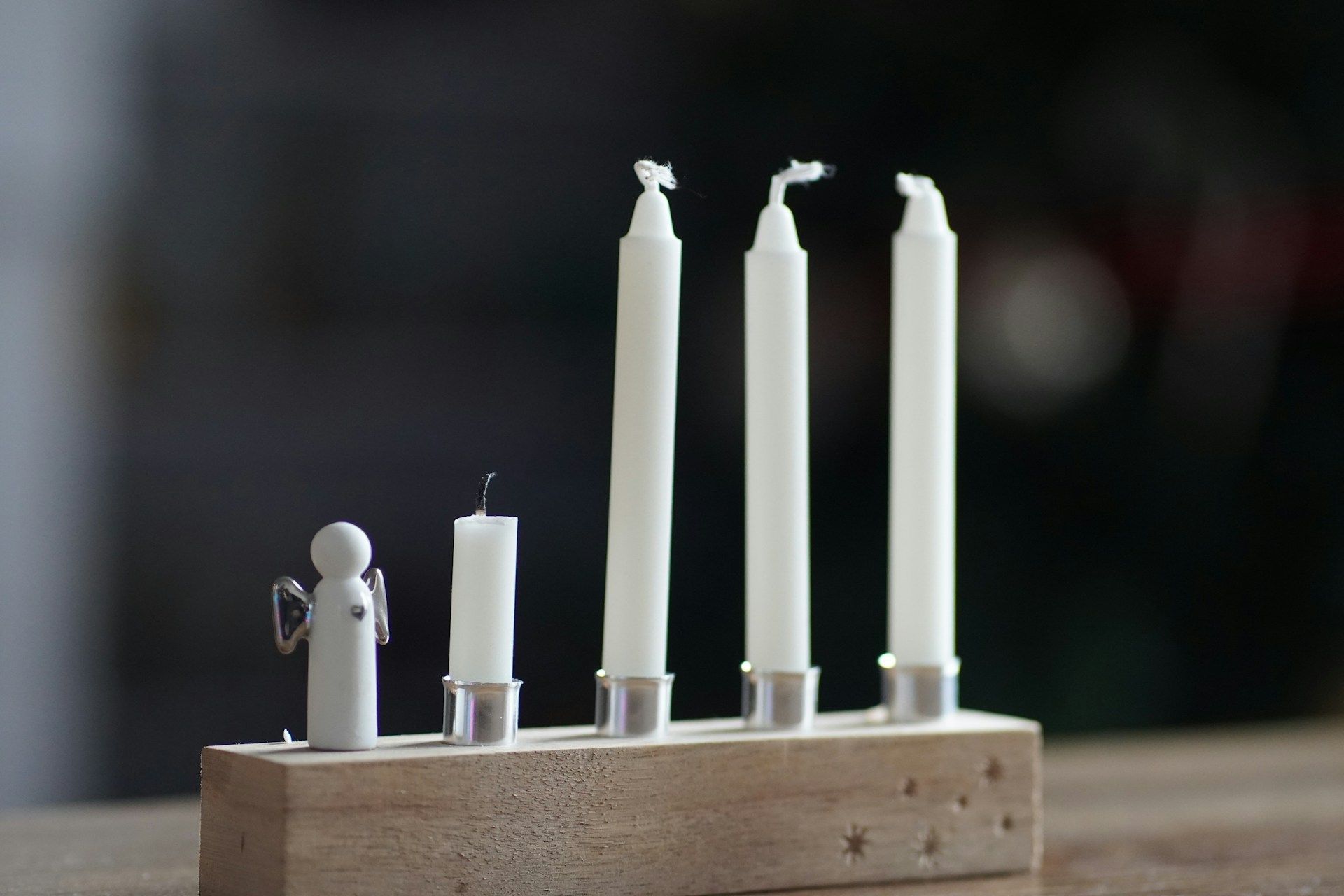 Group of lit candles placed on a wooden block, symbolizing prayer, peace, and remembrance.
