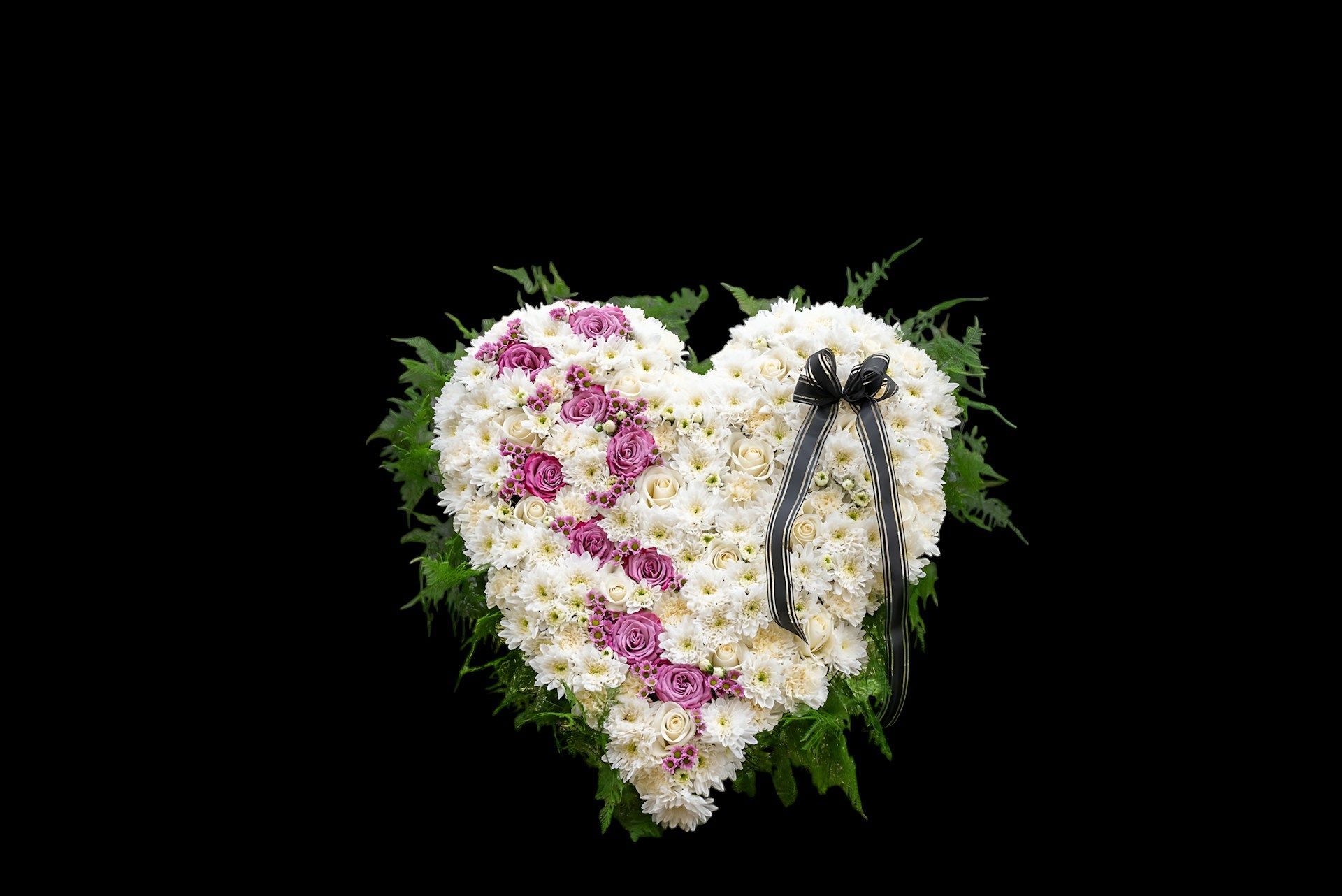 Heart-shaped floral arrangement with white and purple flowers symbolizing love and remembrance.