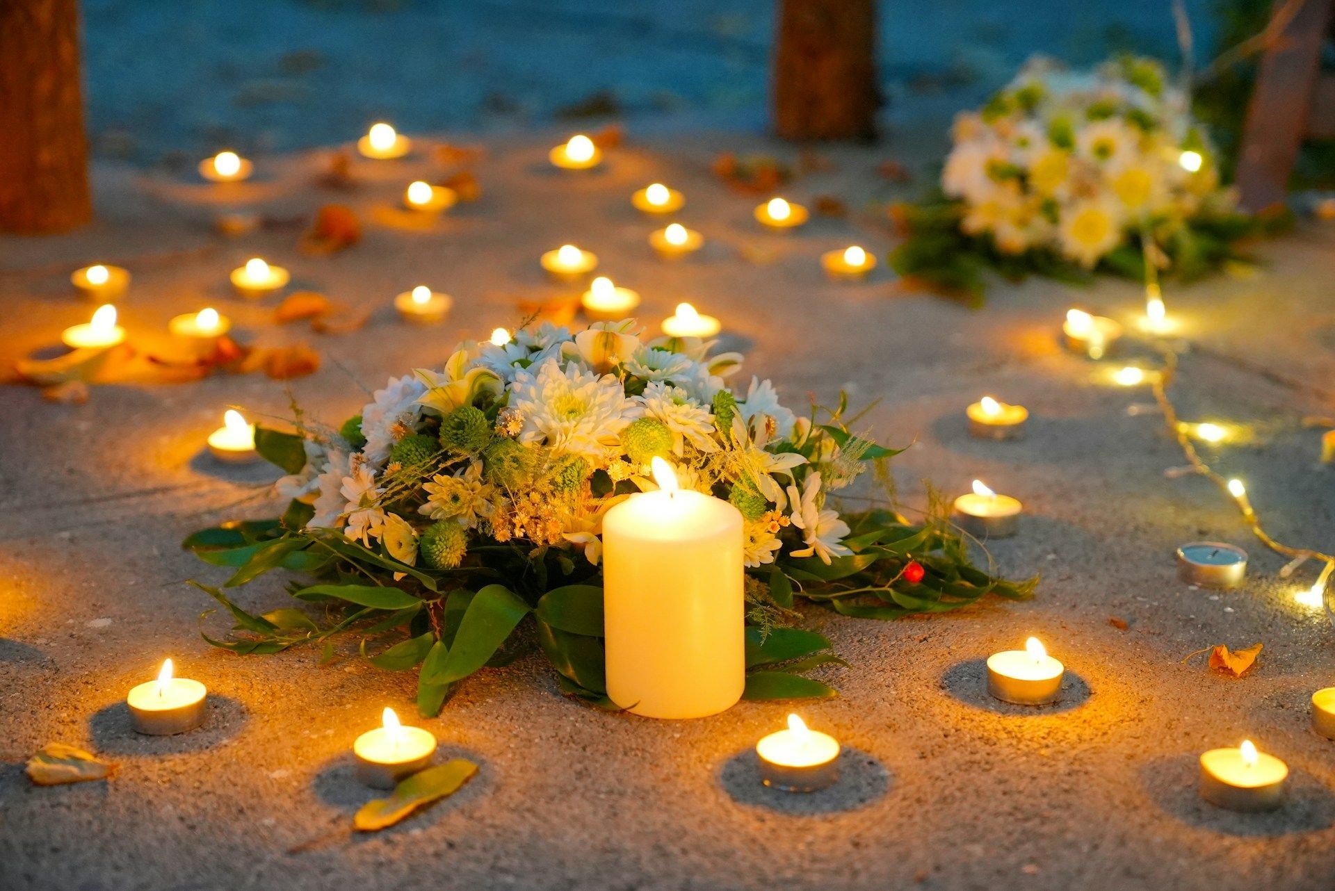 Lit candles placed on the ground in quiet tribute, symbolizing memory, reflection, and homage.