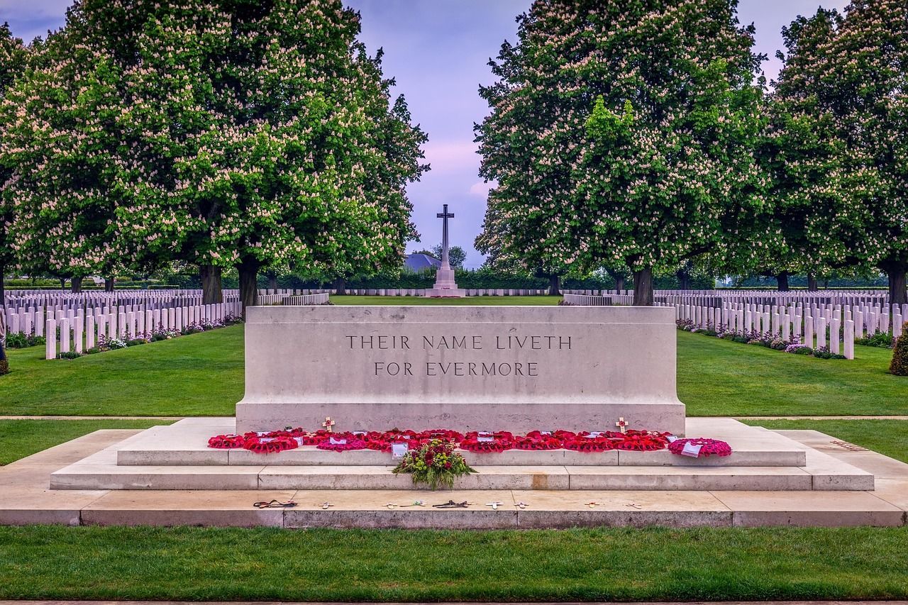 Row of white headstones at Normandy memorial cemetery paying tribute to lives lost in war.