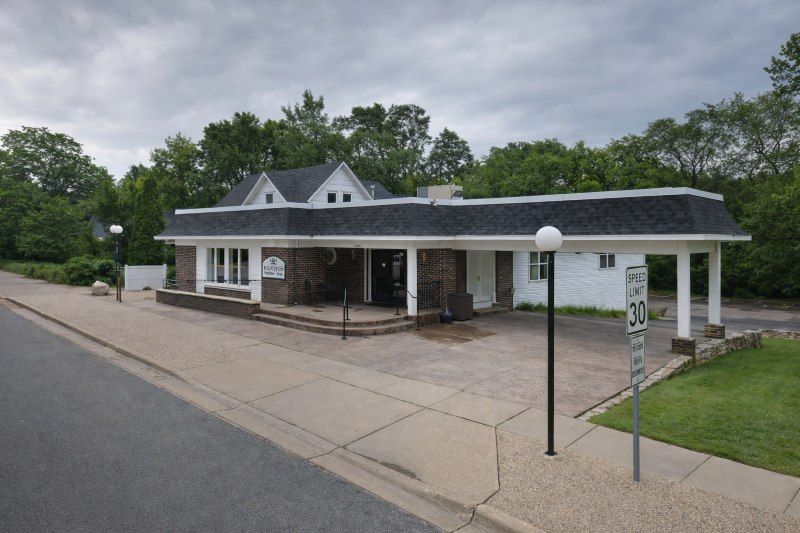 Exterior view of a brick and white building for a Prior Lake, MN funeral home and cremations surrounded by trees and walkways.